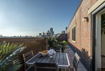 A balcony with a table and chairs and a city in the background
